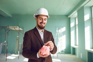 Builder Foreman Putting Coin in Piggy Bank