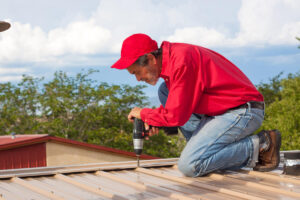 Contractor, builder installing metal panel roof with yellow hardhat